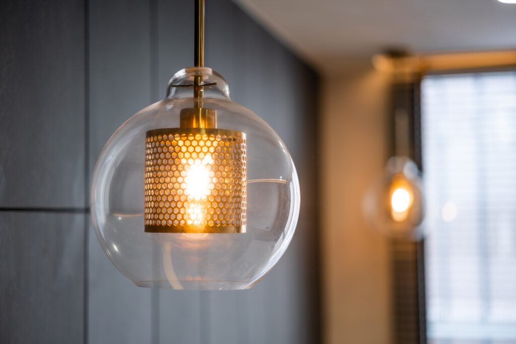 A vintage luxury interior lighting lamp cover featuring a bronze plate and transparent glass bulb, by Mister Sparky of Wilmington.